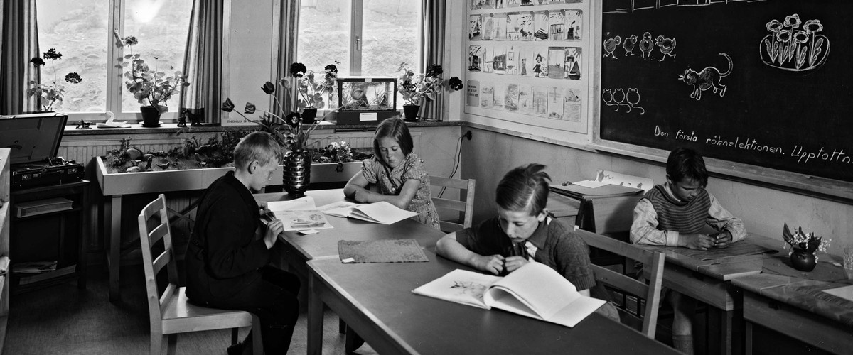 Fyra elever i ett klassrum som studerar. Klassrummet är fyllt av olika lärmaterial.